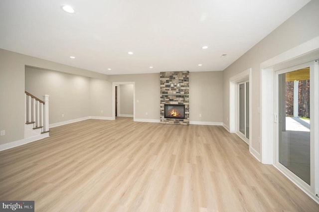 unfurnished living room with a stone fireplace and light hardwood / wood-style flooring