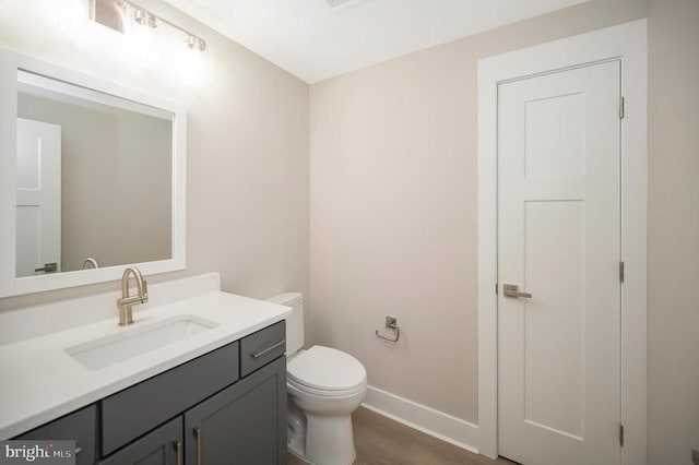 bathroom with wood-type flooring, vanity, and toilet