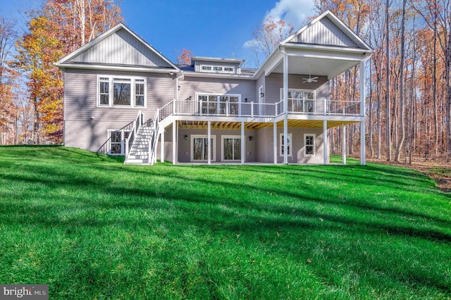 rear view of property featuring a lawn, a wooden deck, and ceiling fan