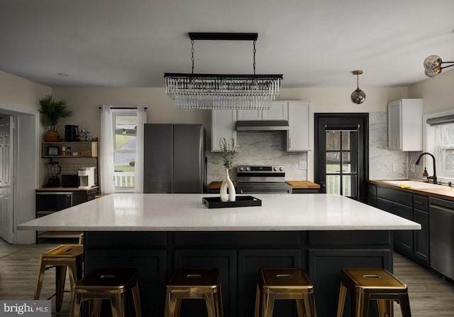 kitchen with a kitchen breakfast bar, stainless steel appliances, sink, white cabinetry, and a kitchen island