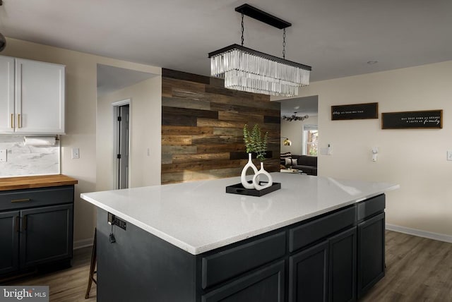 kitchen featuring backsplash, an inviting chandelier, hanging light fixtures, dark hardwood / wood-style flooring, and white cabinetry