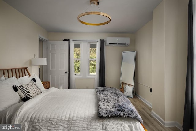 bedroom featuring a wall mounted AC and light hardwood / wood-style floors