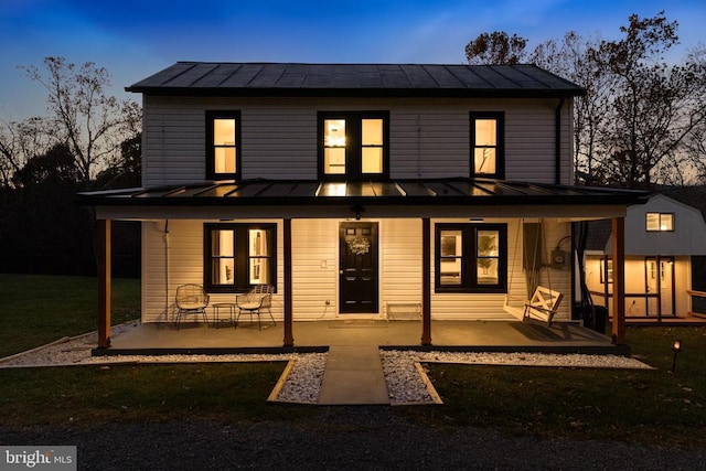 back house at dusk featuring a lawn