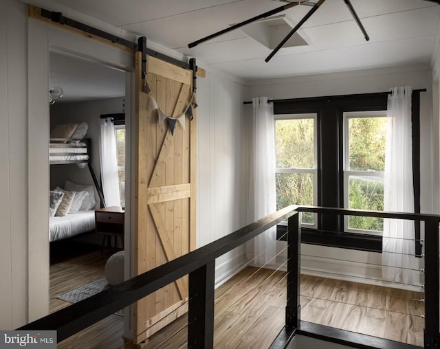 corridor with hardwood / wood-style flooring, plenty of natural light, a barn door, and crown molding