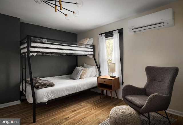 bedroom featuring a wall mounted air conditioner, hardwood / wood-style flooring, and a chandelier