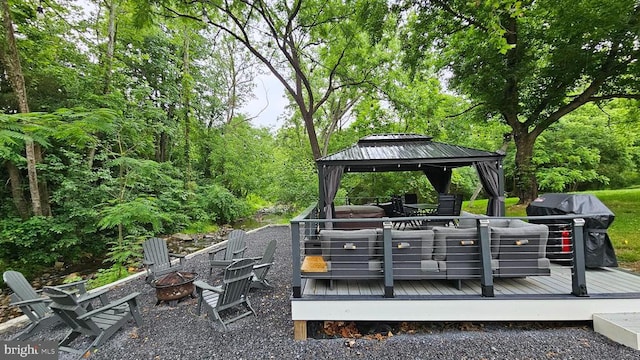 exterior space featuring a gazebo, a wooden deck, and an outdoor fire pit