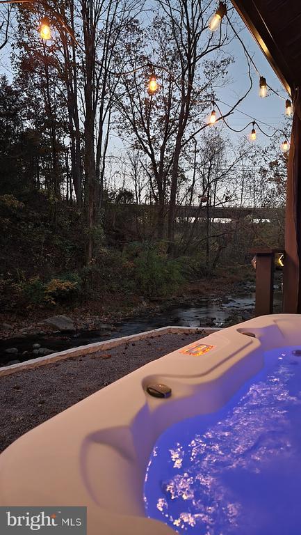 pool at dusk featuring a hot tub