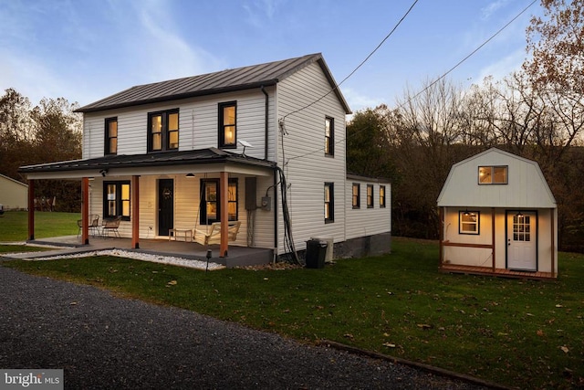 view of front facade featuring covered porch, a yard, and an outdoor structure