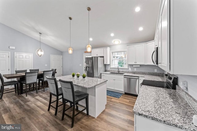 kitchen with white cabinetry, sink, vaulted ceiling, a kitchen island, and appliances with stainless steel finishes