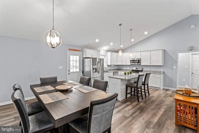 dining space with an inviting chandelier, sink, dark wood-type flooring, and vaulted ceiling