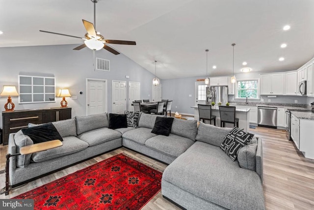 living room featuring ceiling fan, light hardwood / wood-style flooring, and high vaulted ceiling