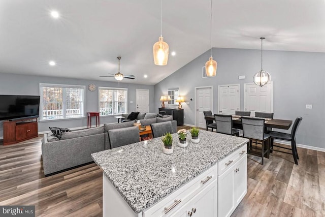 kitchen with pendant lighting, vaulted ceiling, hardwood / wood-style flooring, ceiling fan, and white cabinetry