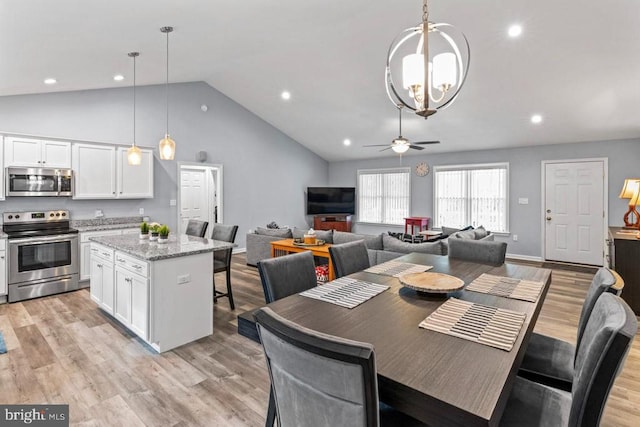 dining room with ceiling fan with notable chandelier, high vaulted ceiling, and light hardwood / wood-style flooring