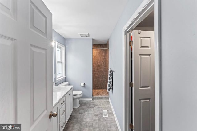 bathroom with tiled shower, tile patterned floors, vanity, and toilet