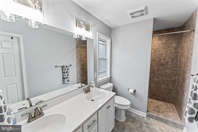 bathroom featuring tile patterned floors, vanity, toilet, and tiled shower