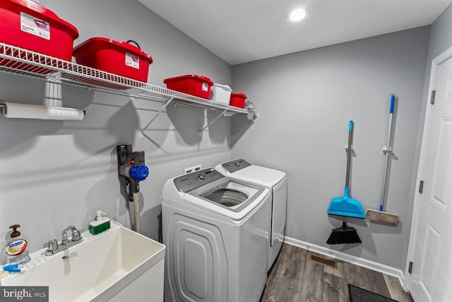 washroom with washer and clothes dryer, dark wood-type flooring, and sink