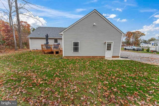 back of property featuring a wooden deck and a lawn