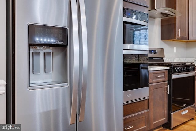 kitchen featuring light hardwood / wood-style floors, range hood, and appliances with stainless steel finishes