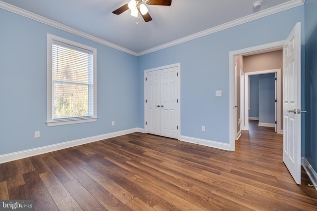 unfurnished bedroom with a closet, ceiling fan, crown molding, and dark wood-type flooring