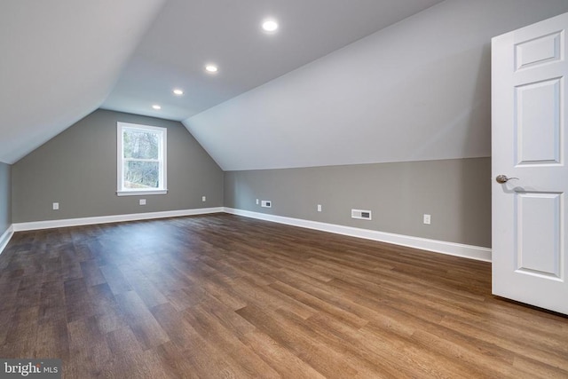 additional living space with hardwood / wood-style flooring and vaulted ceiling