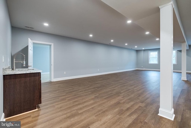 unfurnished living room featuring hardwood / wood-style flooring, decorative columns, and sink