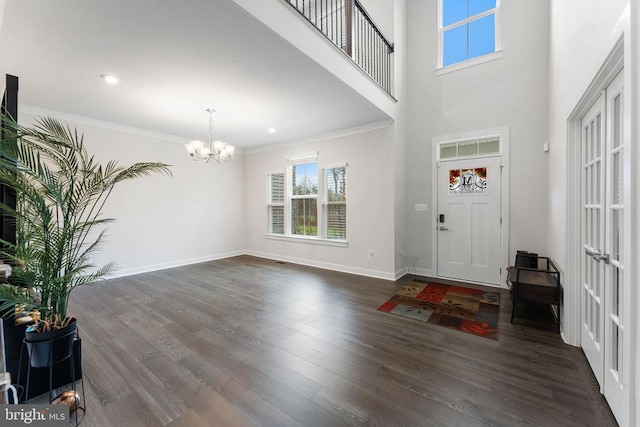 foyer entrance featuring a towering ceiling, dark hardwood / wood-style flooring, crown molding, and a notable chandelier