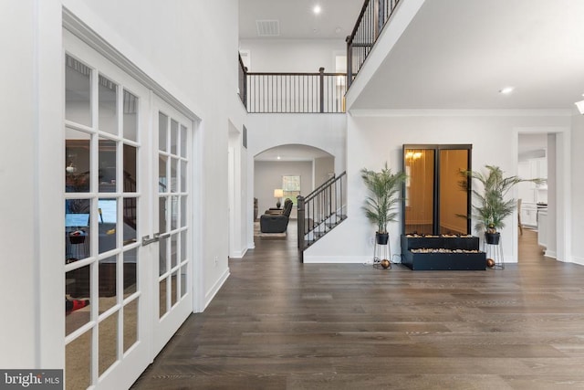 foyer featuring dark hardwood / wood-style floors, a towering ceiling, and french doors