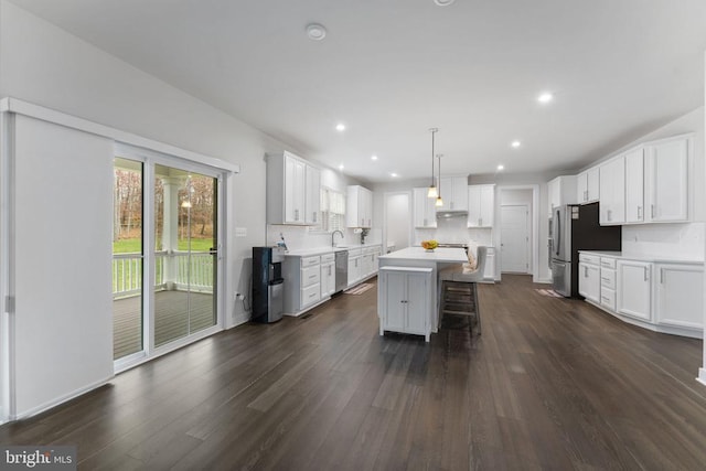 kitchen with a center island, white cabinets, hanging light fixtures, dark hardwood / wood-style floors, and stainless steel appliances