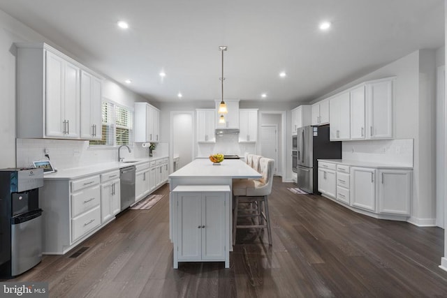 kitchen with dark hardwood / wood-style floors, a kitchen island, white cabinetry, and stainless steel appliances