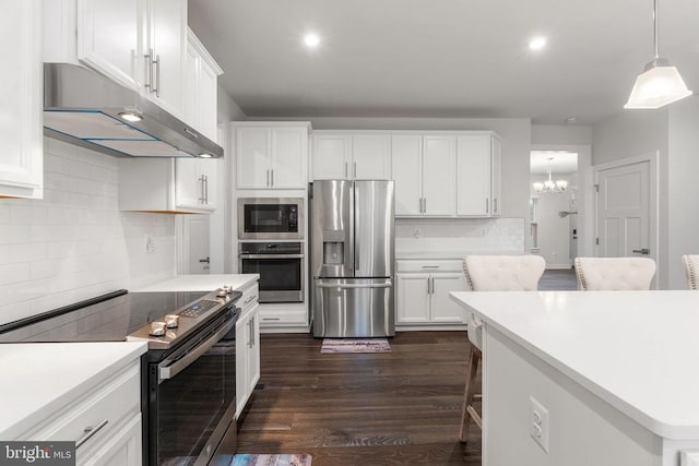 kitchen with backsplash, stainless steel appliances, pendant lighting, dark hardwood / wood-style floors, and white cabinetry