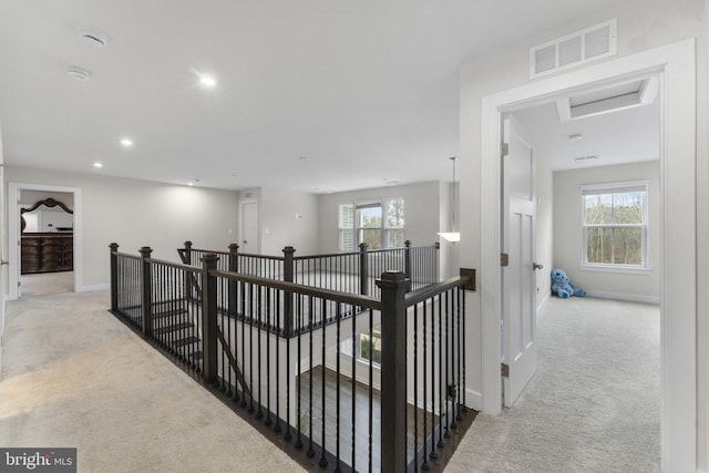 hallway with light colored carpet and plenty of natural light