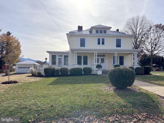 view of front property featuring a garage, covered porch, an outbuilding, and a front lawn