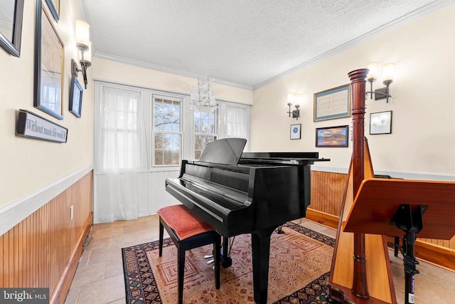 miscellaneous room with a chandelier, wooden walls, a textured ceiling, and ornamental molding