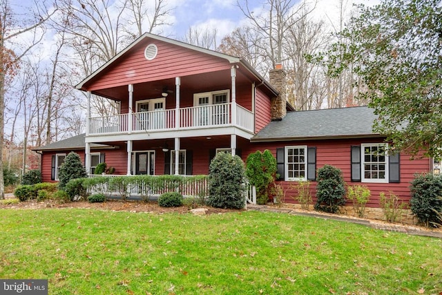 view of front facade featuring ceiling fan, a balcony, covered porch, and a front yard