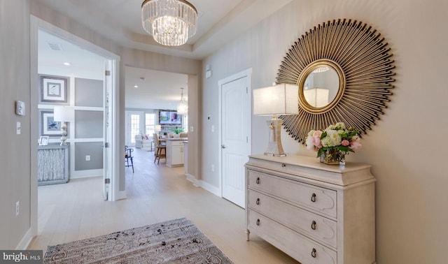 hall with a notable chandelier and light hardwood / wood-style floors