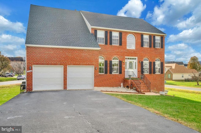 colonial-style house featuring a garage and a front lawn