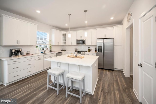 kitchen with hanging light fixtures, white cabinetry, dark wood-type flooring, and stainless steel appliances