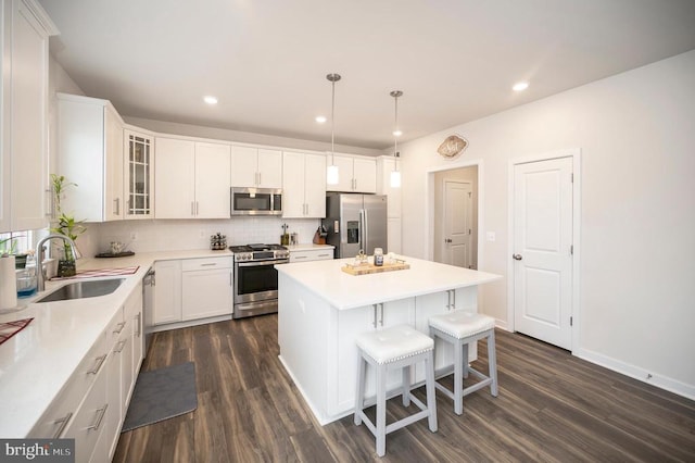 kitchen with sink, a center island, dark hardwood / wood-style flooring, white cabinets, and appliances with stainless steel finishes