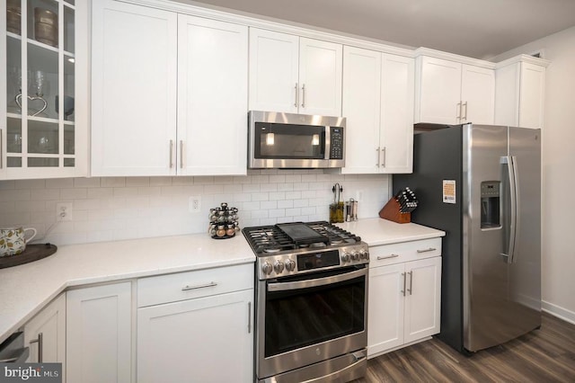 kitchen featuring white cabinets, backsplash, stainless steel appliances, and dark hardwood / wood-style floors