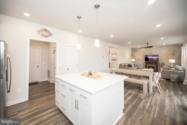 kitchen with white cabinets, stainless steel fridge, hanging light fixtures, and dark wood-type flooring