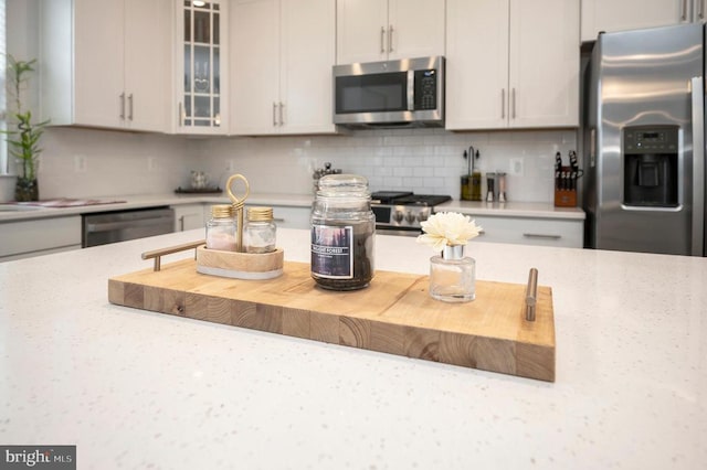 kitchen with white cabinetry, stainless steel appliances, and tasteful backsplash