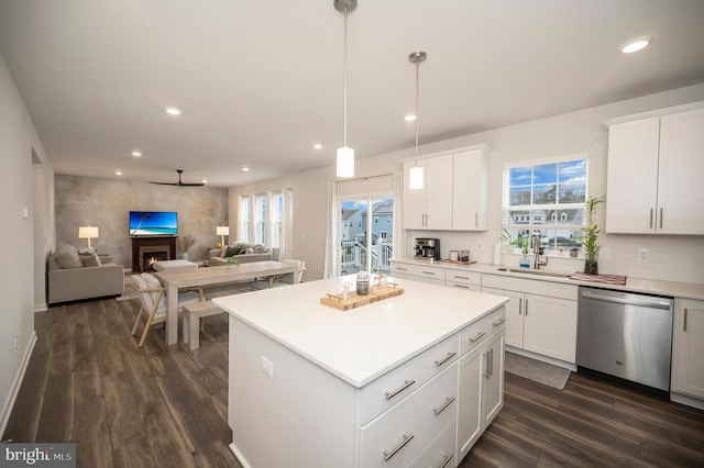 kitchen featuring dark hardwood / wood-style floors, white cabinets, stainless steel dishwasher, and decorative light fixtures