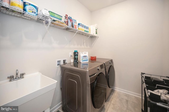 laundry room featuring washing machine and clothes dryer, light tile patterned floors, and sink