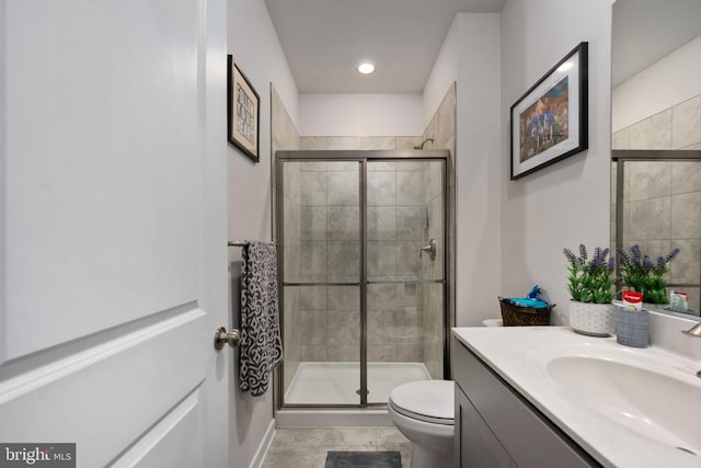 bathroom featuring tile patterned floors, vanity, toilet, and a shower with shower door