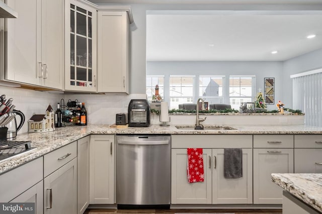 kitchen with light stone counters, sink, stainless steel dishwasher, and plenty of natural light