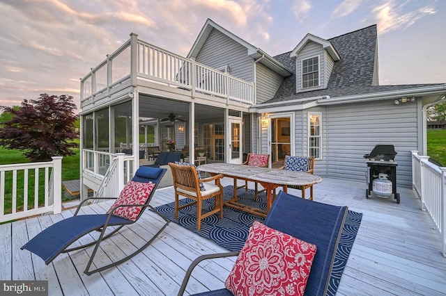 deck at dusk featuring a sunroom