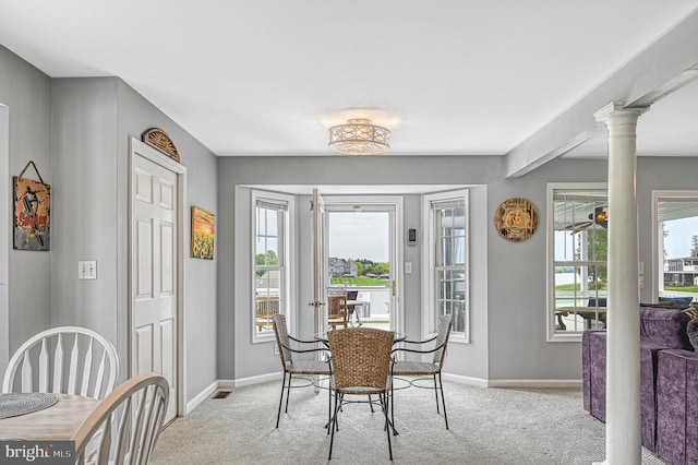 carpeted dining space with beamed ceiling and decorative columns