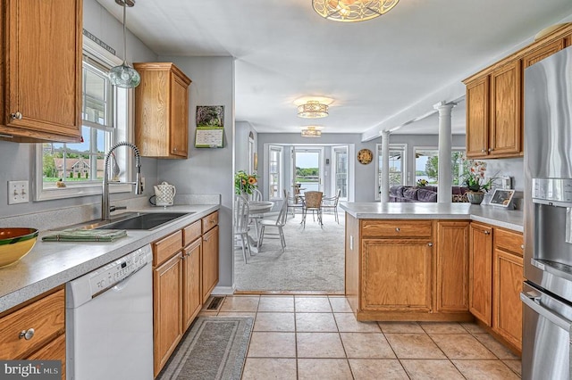 kitchen with dishwasher, sink, hanging light fixtures, decorative columns, and plenty of natural light