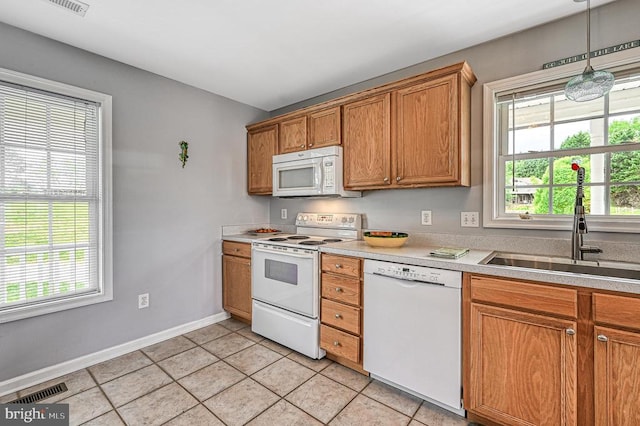 kitchen with a wealth of natural light, sink, light tile patterned flooring, and white appliances