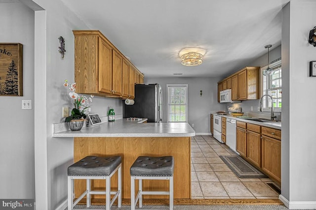 kitchen featuring white appliances, plenty of natural light, a breakfast bar area, and sink